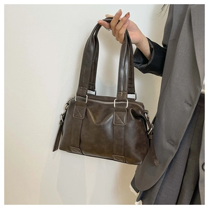 Detail view of deep brown vintage Boston bag featuring matte leather and metal hardware