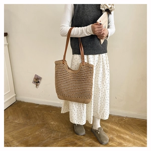 Detailed macro view of the hand-woven straw tote bag with brown leather shoulder straps