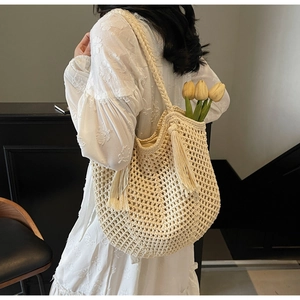 Macro detail of creamy crochet tote bag featuring fringe tassels and woven texture