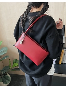 Detail showing red rectangular leather shoulder bag with a silver paisley-shaped pendant