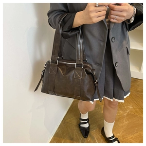 Detail view of a vintage dark brown leather tote bag with wide straps and smooth metal zippers