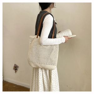 Detail of hand-woven cream tote bag with open-knit patterns and brown leather straps
