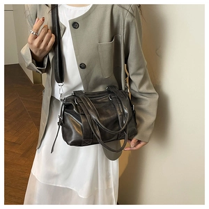 Close-up of a vintage leather Boston bag with silver hardware and adjustable strap
