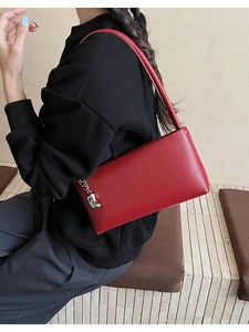 Detail view of a vintage dark red leather baguette bag with a silver animal charm