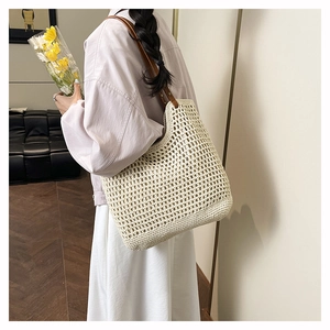 Close-up detail of beige handmade woven tote bag with brown leather shoulder strap