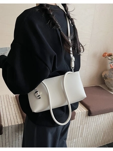 Minimalist white leather shoulder bag with a silver bean charm and adjustable strap