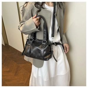 Model wearing a minimalist black tote bag with gray blazer and white dress