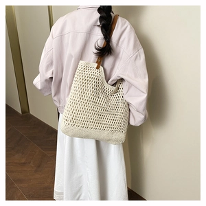 Detail of hand-woven crochet tote bag featuring mesh pattern and brown leather strap