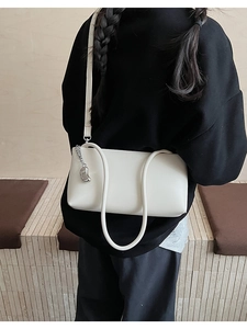 Detail view of white minimalist underarm bag with silver chain pendant on a black hoodie