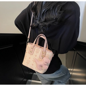 Détail du mini cabas rose avec motif d'étoiles, rivets dorés et breloque ours
