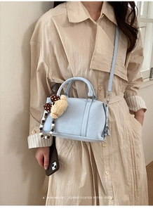 Detail of light blue Boston bag with embossed letters and cute plush bear charm