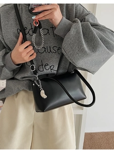 Mirror selfie showing the black leather baguette bag with silver chain accessory