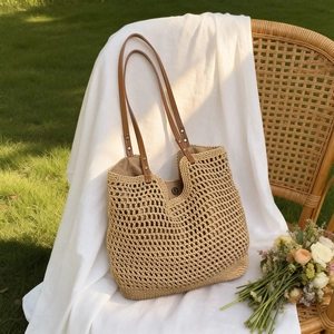 Detail of the straw woven tote bag featuring a magnetic snap closure and faux leather straps