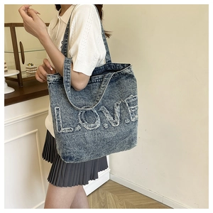 Close-up of vintage washed denim tote bag with embroidered LOVE letters and frayed edges
