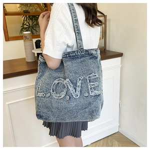 Close-up of vintage washed denim tote bag with frayed LOVE letter embroidery detail