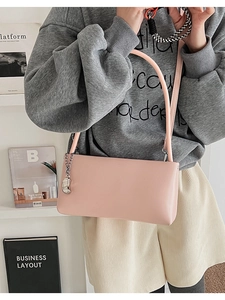Detail of pink faux leather shoulder bag with slim strap and silver charm accessory