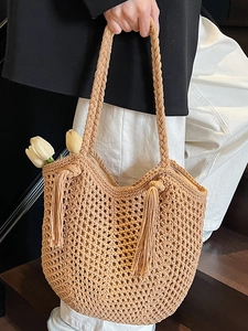 Hollow straw tote bag with woven handles and tassel detail for summer beach vacations