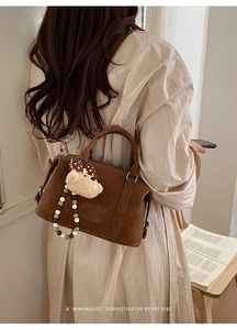 Detail of vintage brown suede Boston bag featuring logo embossing and cute bear pendant