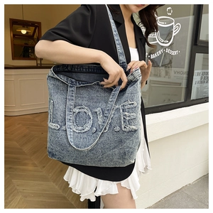 Detail of vintage denim tote bag showing 'LOVE' letter patch and distressed fringe edges