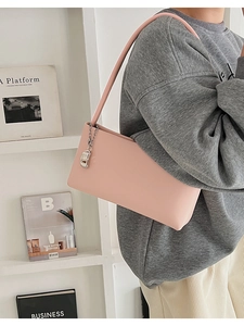 Pink matte leather underarm bag with silver metallic charm shown on a female model