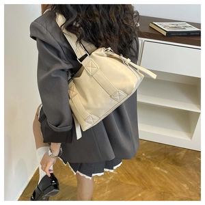 Detail of beige faux leather tote bag with geometric stitching on a shoulder strap