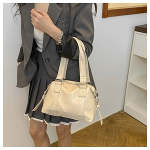 Detail of a creamy leather tote bag showing the matte texture and reinforced handle straps
