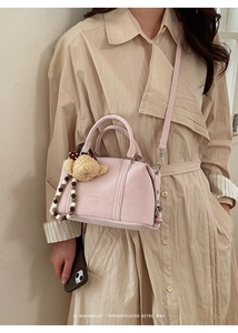 Detail of light pink Boston bag with plush bear charm and beaded chain on adjustable strap