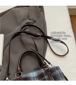 Detail of adjustable leather shoulder strap and blue plaid fabric on a vintage handbag