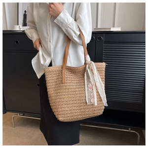 Dettaglio borsa tote in paglia intrecciata con manici in pelle e sciarpa in pizzo fiorito
