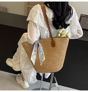 Detail of hand-woven straw tote with brown leather strap and decorative silk scarf