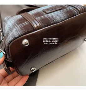 Detail view of durable plaid handbag bottom with protective metal studs and leather finish