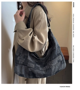 Detail of high-capacity woven tote bag with patchwork texture on woman's shoulder