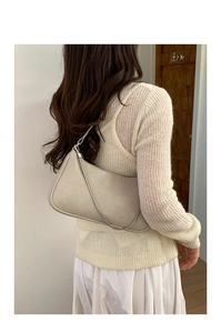 Détail d'un sac à bandoulière minimaliste en similicuir beige avec chaîne décorative