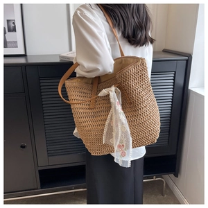 Dettaglio della borsa tote in paglia intrecciata con sciarpa in pizzo e manici in pelle