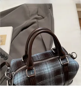 Detail of retro plaid handbag showing the dark brown leather handle and silver metal hardware