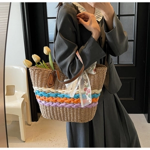 Detail shot of handwoven straw tote bag with colorful ribbons and leather handles