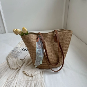 Detail of hand-woven straw tote with brown leather straps and bohemian silk scarf accent