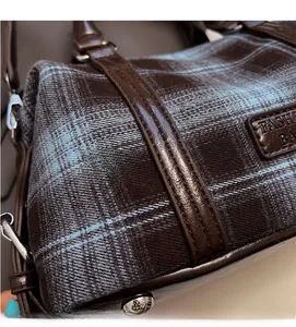 Detailed macro view of vintage plaid fabric texture and dark brown leather stitching