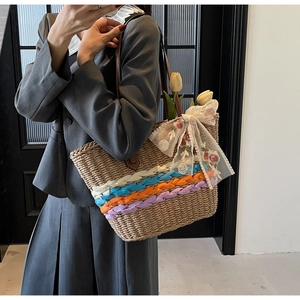 Detail of large straw tote bag with colorful woven bands and white lace floral bow