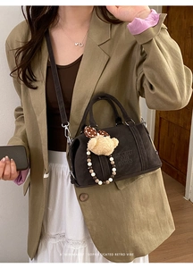 Close-up of vintage dark brown Boston bag with plush bear charm and brand embossing