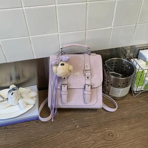 Close-up of lavender mini crossbody bag with metal buckles and plush bear charm