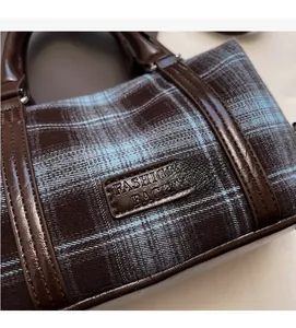 Detail of vintage plaid fabric handbag with brown leather trim and fashion tag