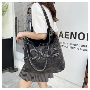 Detailed view of the frayed edge denim tote bag with LOVE embroidery and vintage wash finish
