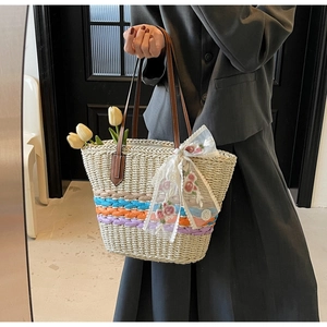 Detail of hand-woven straw tote with leather handles and white lace floral bow