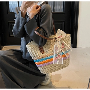 Detail of hand-woven straw tote bag with lace flower embroidery and leather handles
