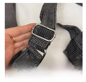 Detail of adjustable woven shoulder strap with silver metal buckle on denim tote bag