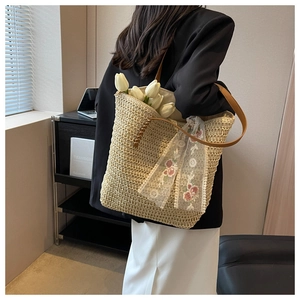 Dettaglio macro della borsa tote in paglia intrecciata con nastro in pizzo e pelle