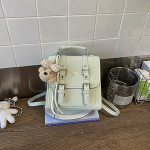 Detail of mint green PU leather backpack with silver buckles and a cute plush bear charm