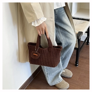 Detail of dark brown knit handbag with chunky wool texture and Hand Made leather tag