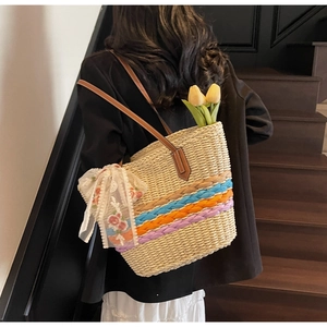 Detail of hand-woven straw tote with colorful stripes and floral lace bow decoration